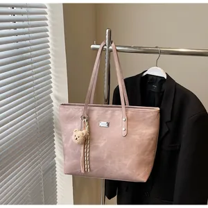 Detail view of light pink tote bag with teddy bear pendant and tassel hanging on a rack