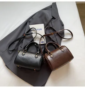 Close-up of vintage Boston bags in black and dark brown with retro gold metal hardware