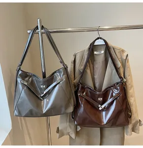 Détail de sacs cabas en cuir brillant gris et marron suspendus à un support en métal