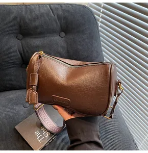 Detail of dark brown boston bag with herringbone strap and textured synthetic leather