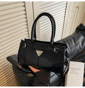 Close-up of black glossy patent leather handbag with triangle metal plaque detail