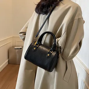 Classic black Boston bag with lychee texture and gold hardware on model's shoulder