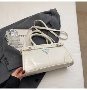 Close-up of cream PU leather handbag with metal triangle logo on a grey blazer