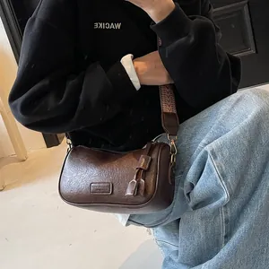 Retro brown shoulder bag with textured leather and printed wide strap on model