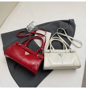 Detail shot of solid color satchels in red and beige with metallic triangle accent