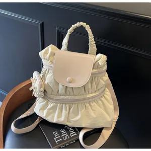Dettaglio zaino in nylon beige a pieghe con patta in pelle e un piccolo borsellino tondo