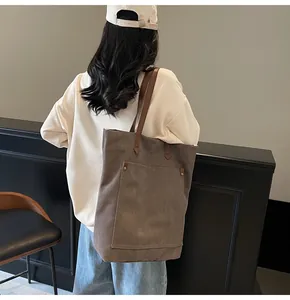 Detalle de un bolso tote grande de lona marrón con correa de cuero y bolsillo