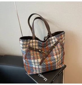 Nahaufnahme der blauen und orangefarbenen Tweed-Textur und Lederriemen der Tragetasche