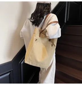 Detalle del bolso tote de lona caqui grande con asas de cuero y remaches metálicos
