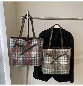 Detailaufnahme von Tweed-Stofftaschen mit Lederriemen und Metallschnalle an einem Gestell