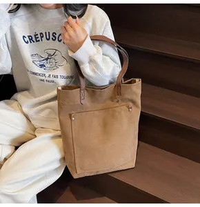 Detalle del bolso tote de lona marrón oscuro con bolsillo delantero y remaches metálicos