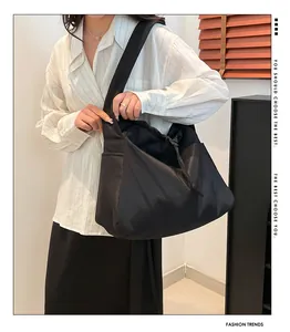 Detail view of a black drawstring crossbody bag with side pocket and sleek nylon texture