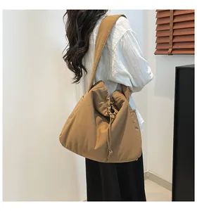 Detail of khaki drawstring tote bag showing flexible ruched nylon fabric on model