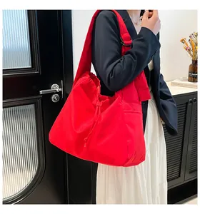 Detailed view of bright red nylon tote bag with drawstring pleated design on model