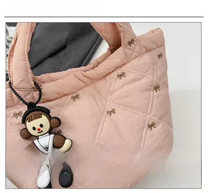 Close-up of pink quilted puffer bucket bag showing embroidery and plush charm detail
