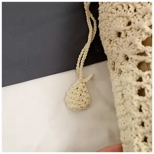 Detail of hand-woven cream bucket bag featuring hollow crochet pattern and woven drawstring balls
