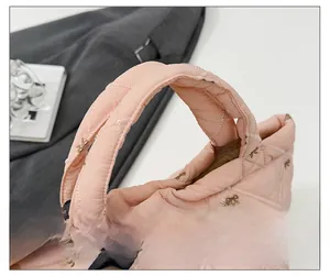 Detail of pink quilted puff bucket bag handle with delicate butterfly embroidery