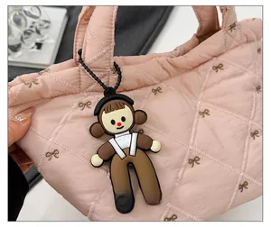 Detail showing a cute brown cartoon character charm with headphones on a quilted bag