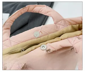 Detail of pink quilted bucket bag showing magnetic snap closure and inner zip pocket