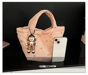 Detailed macro view of pink quilted bucket bag with bow embroidery and cartoon doll charm