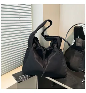 Detail of black pleated drawstring tote bag featuring waterproof nylon and side pockets