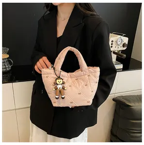 Detail shot of light pink quilted bucket bag with a cute charm accessory on model