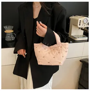 Detail of quilted light pink handbag featuring delicate bow prints and soft puffy texture