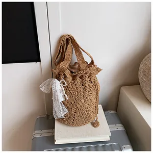 Detail of hollow woven bucket bag featuring white lace bow and faux pearl accents
