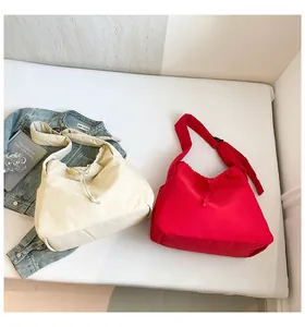 Flat lay of cream and red nylon drawstring tote bags with adjustable shoulder straps