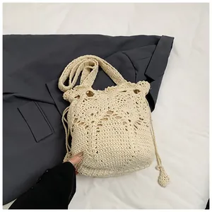 Detailed close-up of cream crochet bucket bag with hollow woven texture and drawstring
