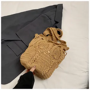 Detail of hand-woven straw bucket bag with hollow pattern and drawstring closure
