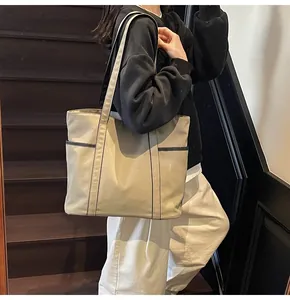Detailansicht der Canvas-Tragetasche mit Vordertaschen an der Schulter des Models