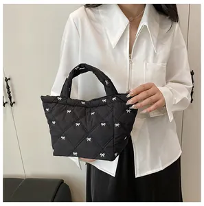 Close-up of black quilted bucket bag featuring white bow patterns and elegant texture