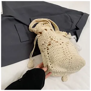 Detail view of cream crochet bucket bag with intricate hollow woven texture and lace pendant