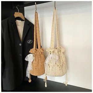 Close-up of hollow woven bucket bag with lace bow and pearl charm detail