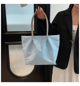 Detail of light blue waterproof nylon tote bag with golden button and beige handles