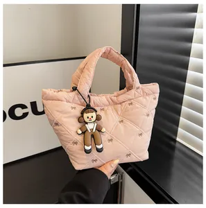 Detailed close-up of pink quilted bucket bag with bow embroidery and a cute charm