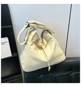 Detail of a creamy white puffy tote bag featuring drawstring closure and soft nylon fabric