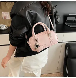 Detail of pink glossy leather Boston bag with heart charm and shoulder strap
