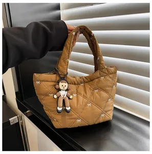 Detail of brown quilted puffer bucket bag with white bows and a cute plush charm