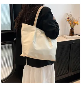 Detail of cream nylon tote bag showing thick round straps and metallic eyelets on side