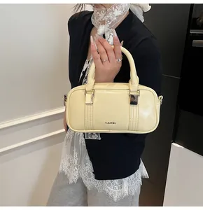 Detail of cream yellow boston bag in glossy finish with metal D-rings and brand logo