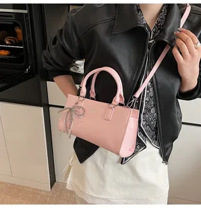 Rosa CHIC V Umhängetasche mit Schleifenanhänger getragen über einer schwarzen Lederjacke