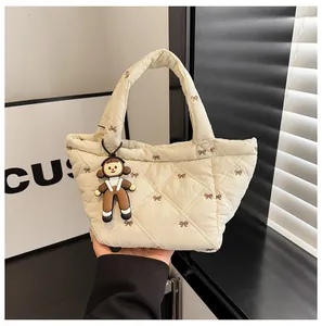 Close-up of cream quilted bucket bag featuring embroidered bows and cute girl charm