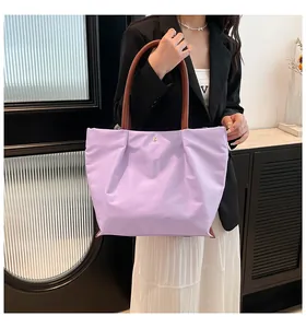 Detail of light purple waterproof nylon tote bag with brown leather straps and metal button