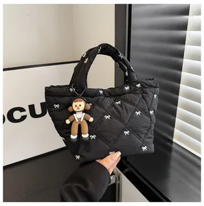 Close-up of black quilted puff bucket bag featuring white bow prints and a cute charm