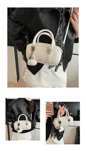 Detail of white Boston bag with heart charm and brand logo on glossy leather finish