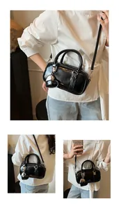 Detail of black glossy cylindrical pillow bag with heart pendant and adjustable strap