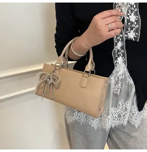 Detail der beigen Lederhandtasche mit Perlenbogen, Schlüsselanhänger und CLEARMK Logo
