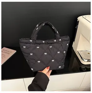 Close-up of black quilted bucket bag with white bow embroidery and padded handle details